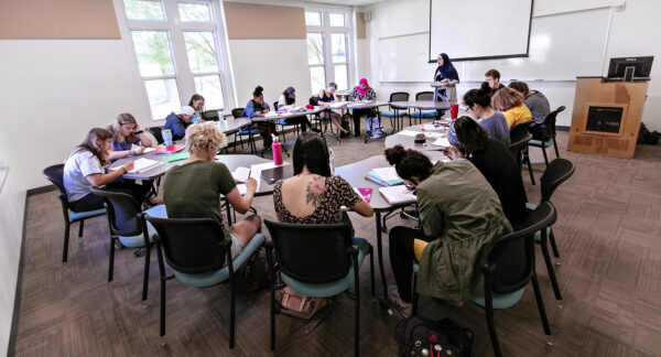 a group of students sitting at desks arranged in a circle in a classroom