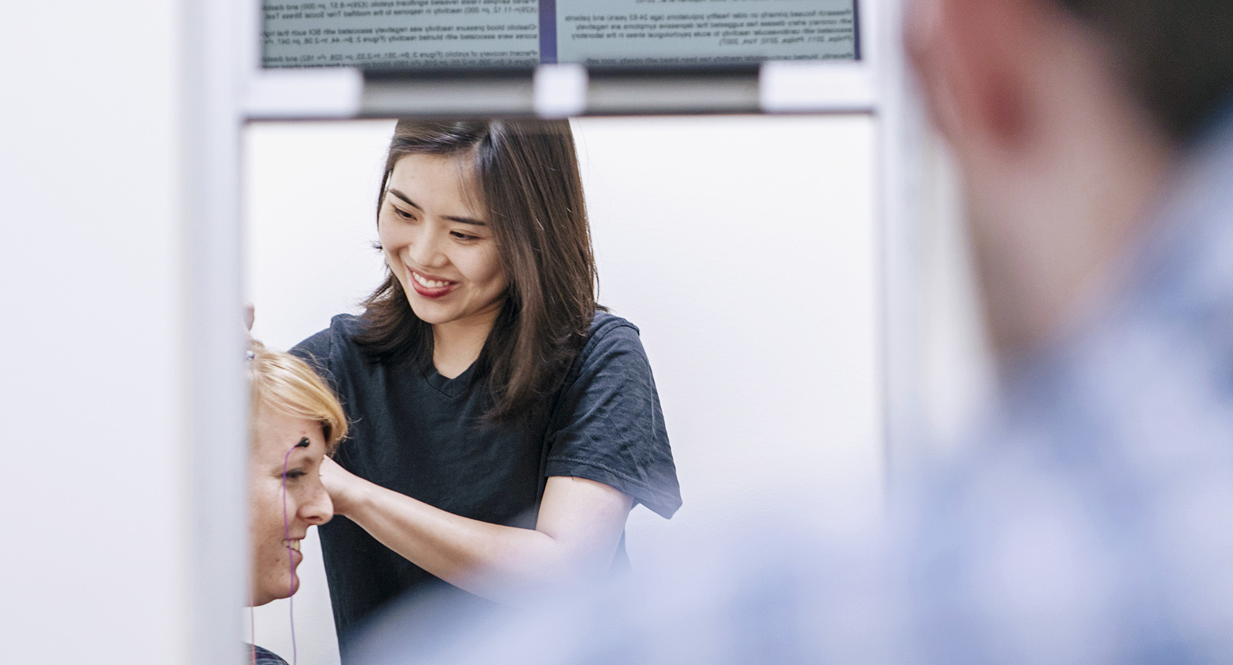 a person attaching electrodes to the forehead of a woman