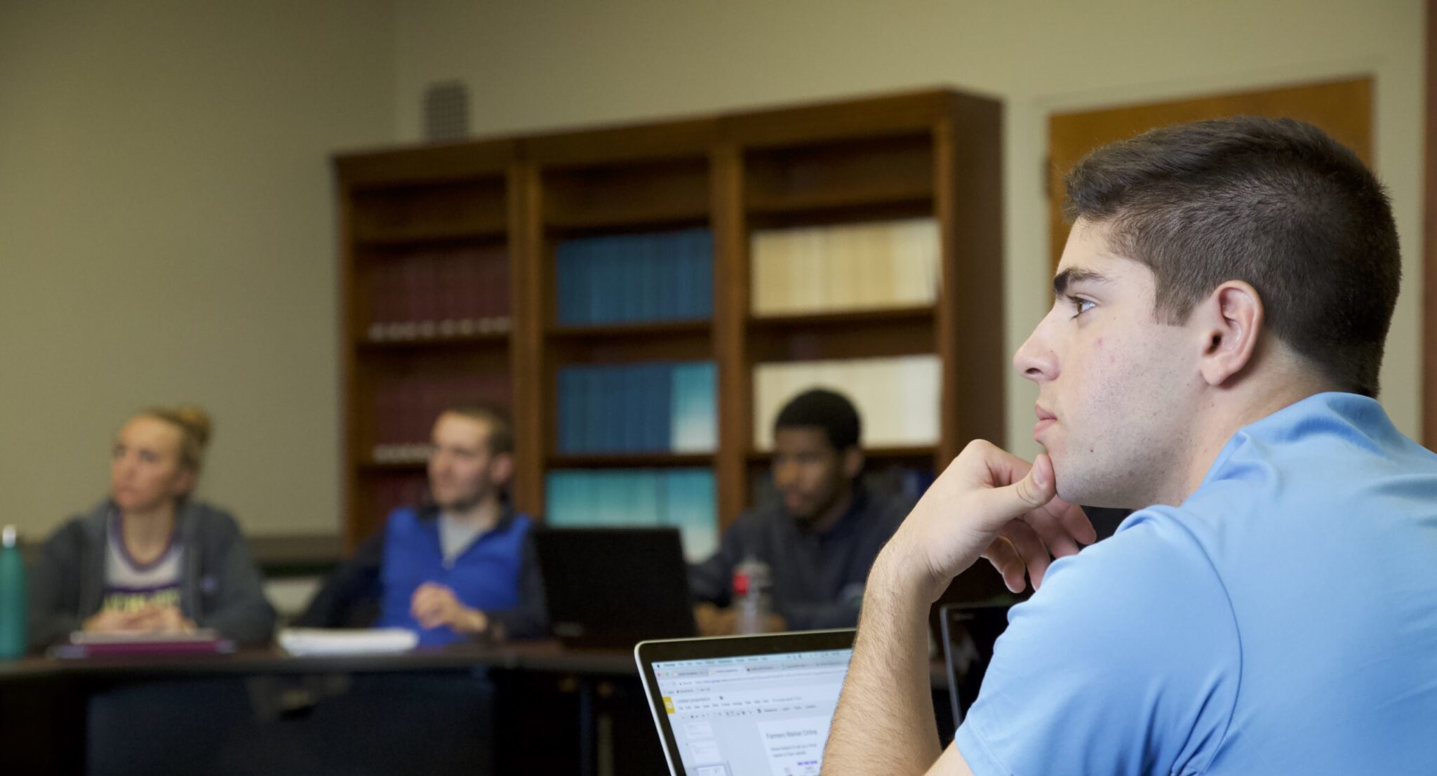 a student in a blue shirt with his hand on his chin