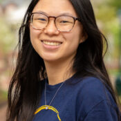 Smiling woman with long dark hair in glasses and navy blue shirt