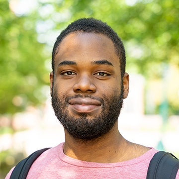 a person with a beard wearing a pink shirt