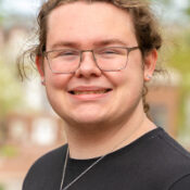 Smiling man with hair pulled back wearing black shirt