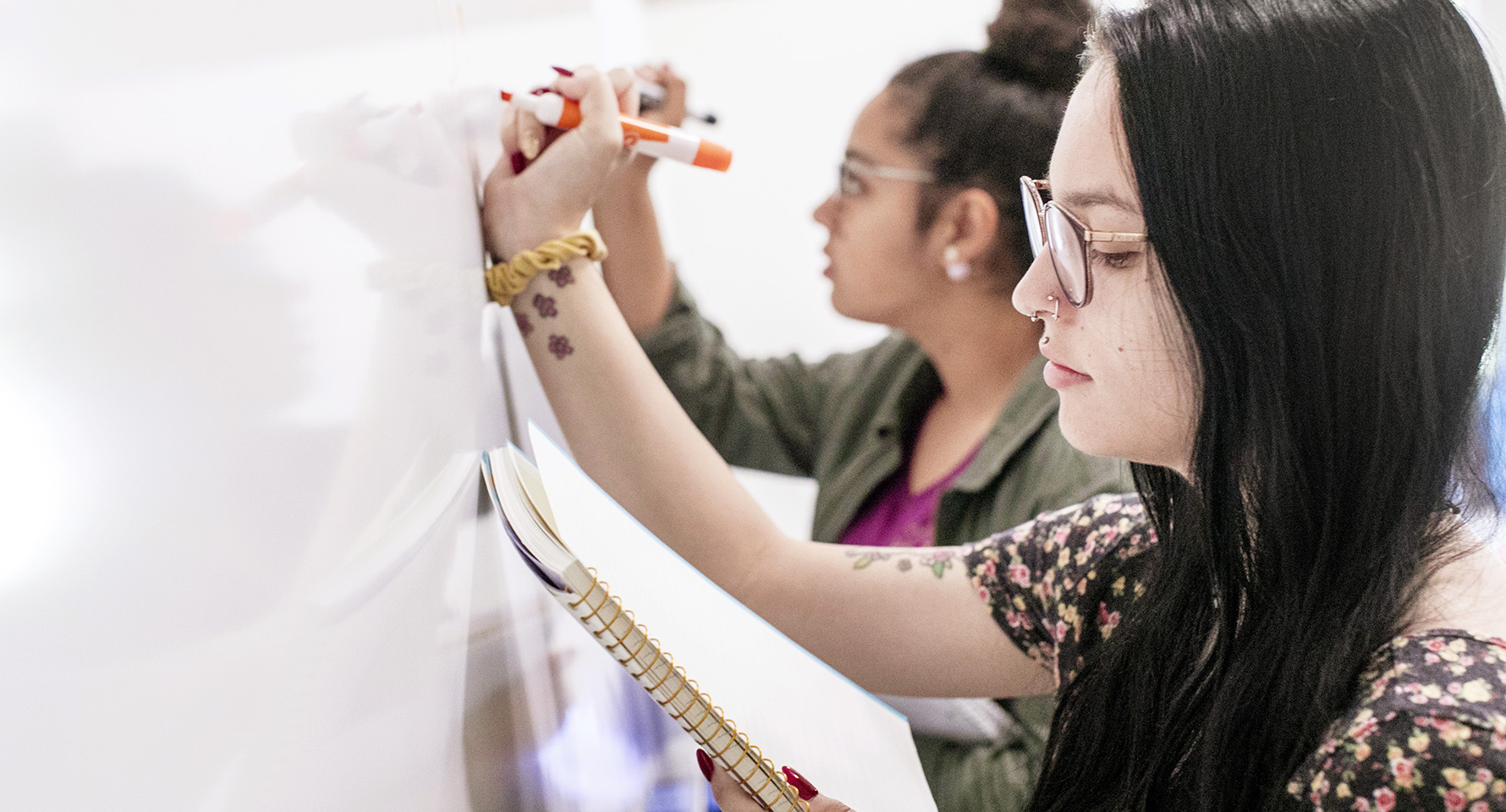 two students writing on a whiteboard