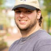 Smiling man in baseball cap and gray shirt