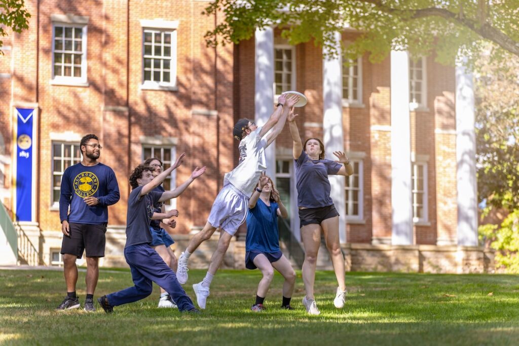A group of people jump up to catch a frisbee