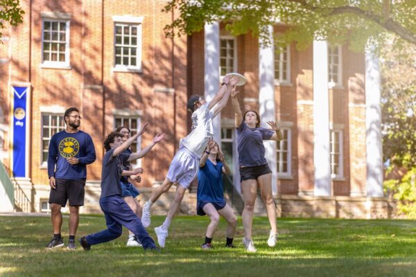 A group of people jump up to catch a frisbee