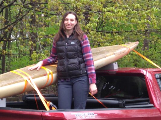 a person standing in the back of a pickup truck with a surfboard