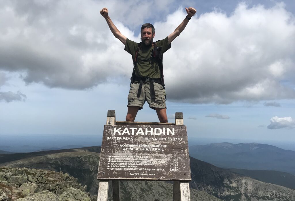 a person standing on a sign with his arms raised