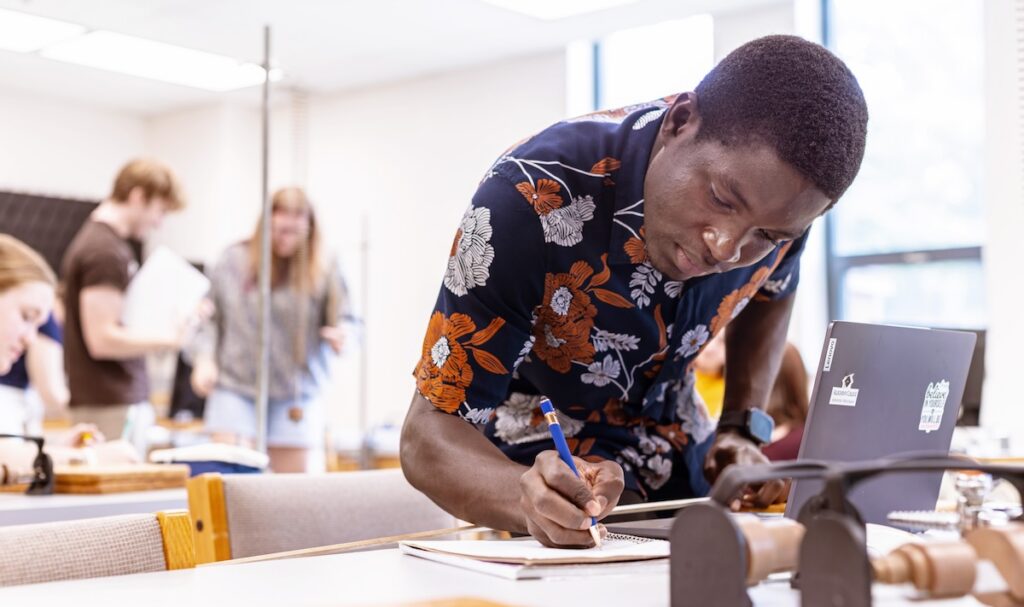 An Allegheny College student makes notes in at a lab table
