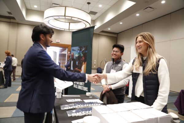 An Allegheny College student shakes hands with an alumni at a Pittsburgh career fair