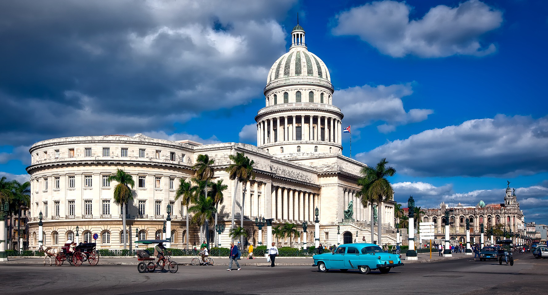 A capitol building with a white dome and a blue car