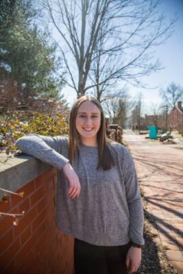 a student leaning against a brick wall