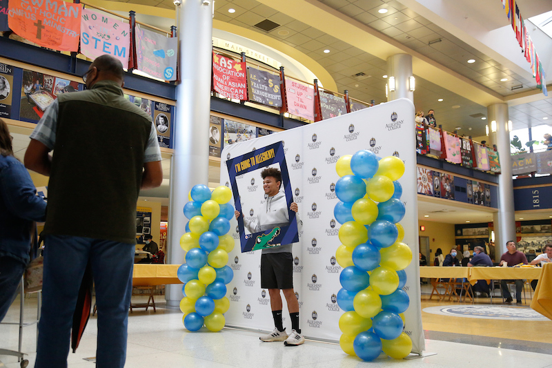 student holding a frame reading "I'm going to Allegheny" with balloons on either side of him