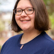 Woman with short brown hair and glasses facing to the left