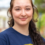 Smiling woman with long brown hair wearing navy blue shirt