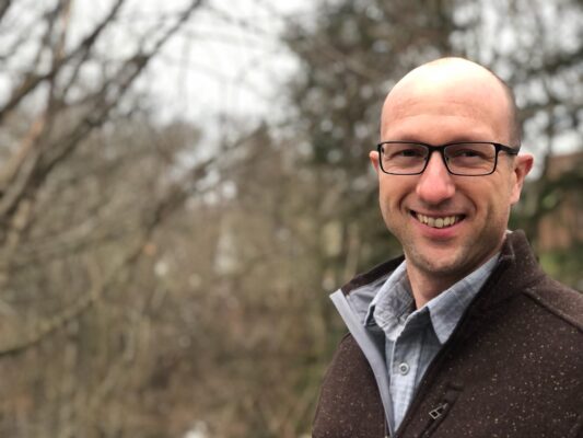 a person wearing glasses and a brown jacket