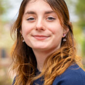 Smiling woman with long hair wearing a navy blue shirt and earrings