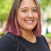 Headshot of woman with pink hair facing to the right