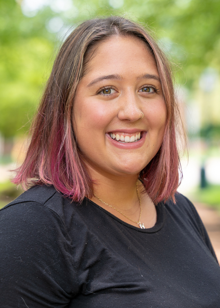 Headshot of woman with pink hair facing to the right