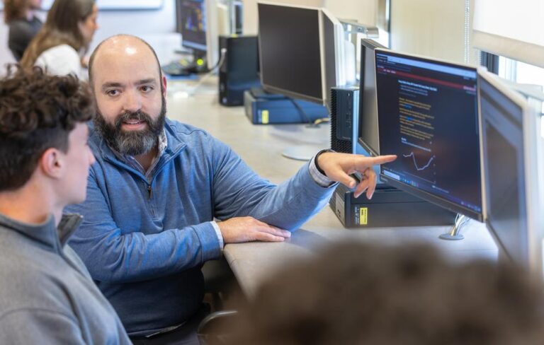 professor and student talking and looking at a computer screen
