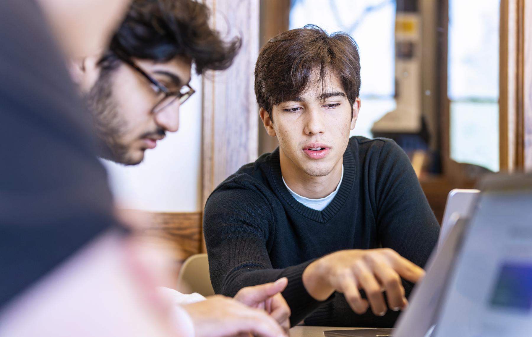 a group of students looking at a laptop