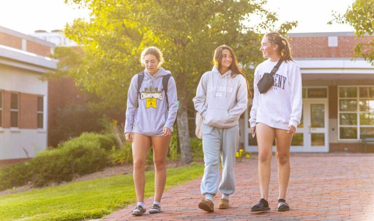 three students walking on campus with lots of greenery