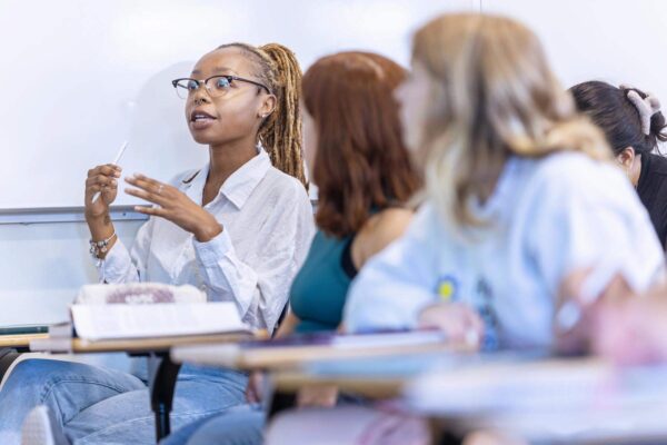 a student in a white shirt speaking to a group of people