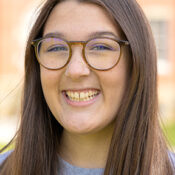 Smiling woman with long brown hair and round glasses