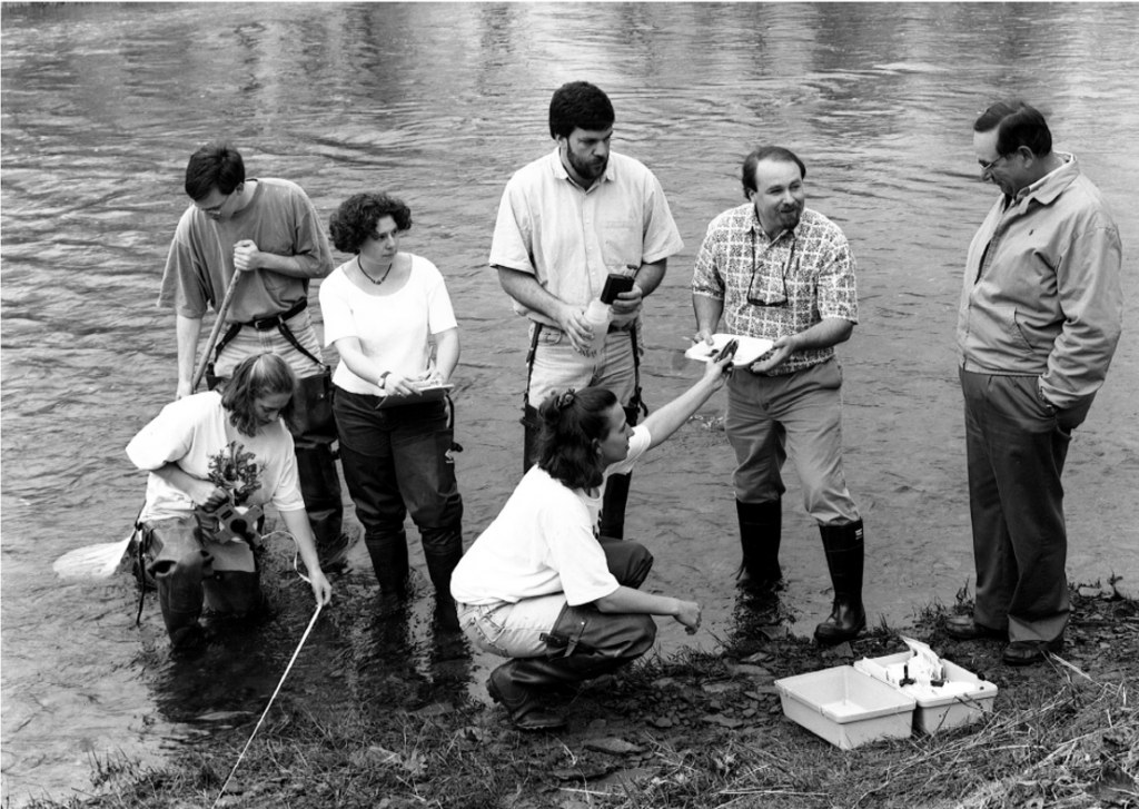 black and white photo of a group of people standing in water