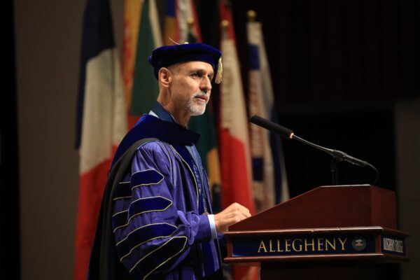 Allegheny College President Ron Cole stands a podium wearing regalia during the Class of 2030 Matriculation