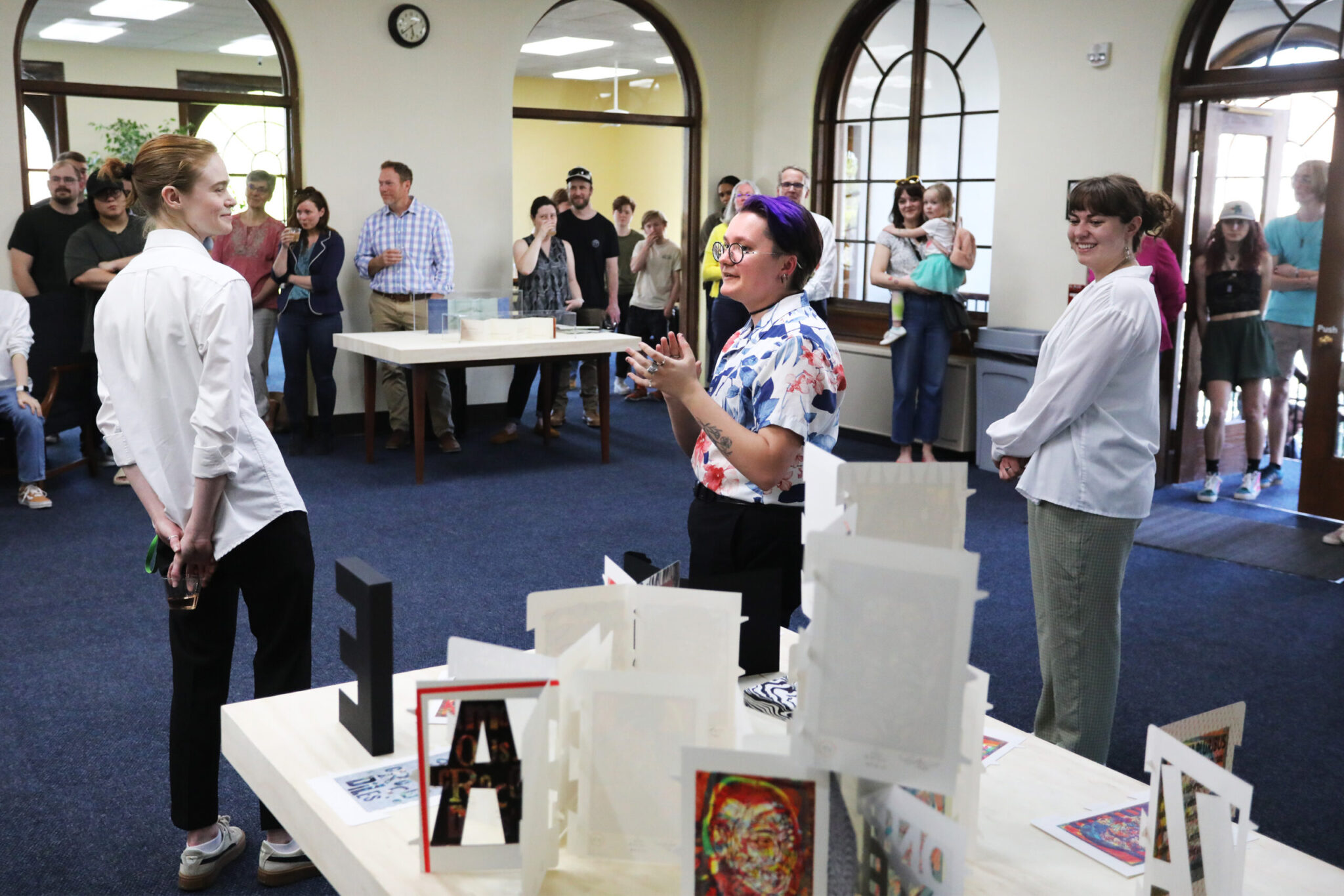 a person standing in front of a table with white paper while others look on