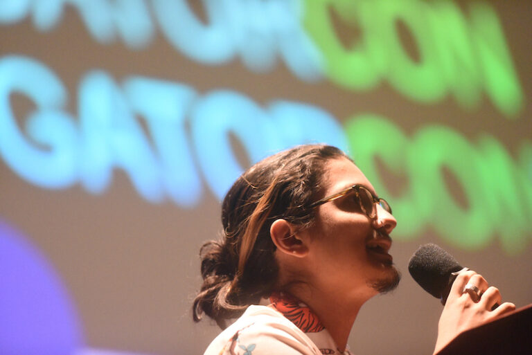 student holding a microphone with a screen reading 