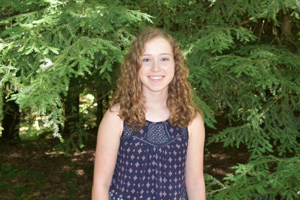 a student standing in front of trees