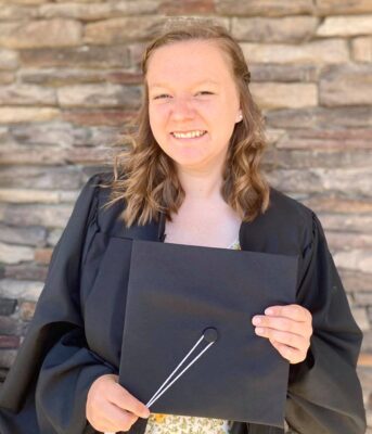 a person in a black robe holding a black graduation cap