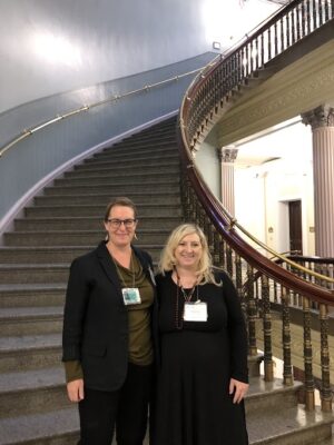 two women standing in front of a staircase