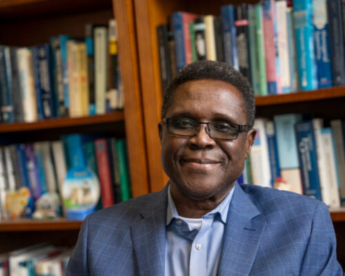 Headshot of Steve Onyeiwu with a bookshelf in the background