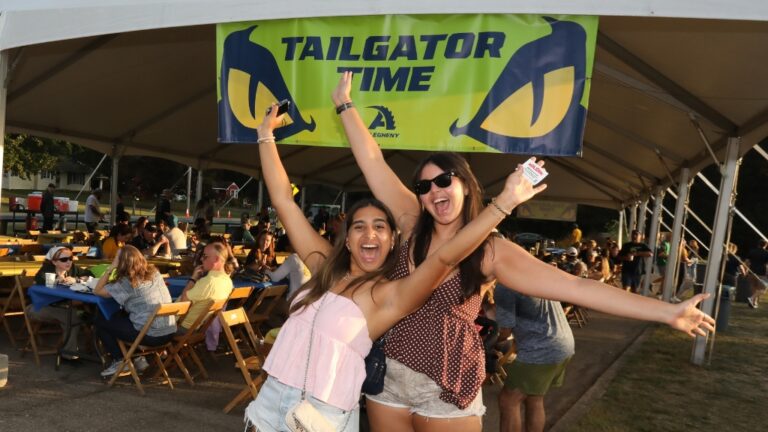 Two Allegheny College students stand in front of a sign that reads 