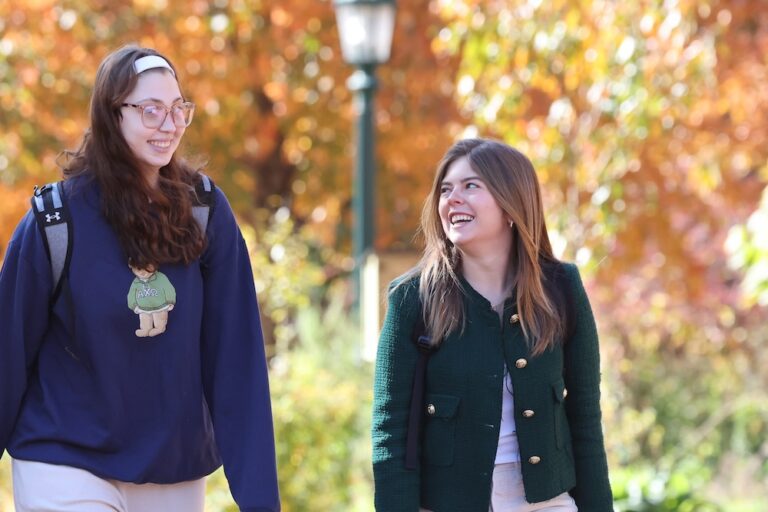 Two Allegheny College students walking across the college campus in the fall