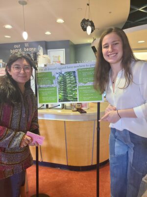 two women standing next to a research poster