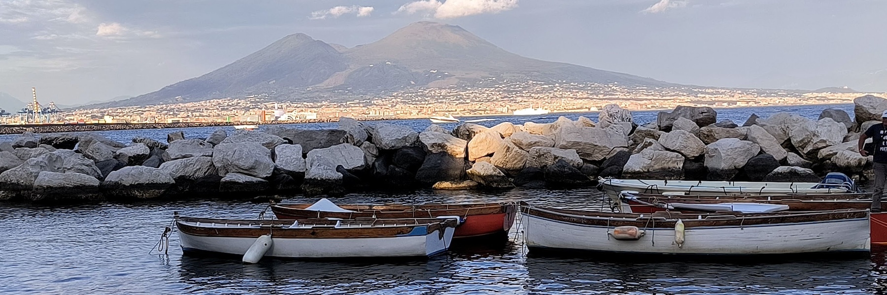 Two boats on the coastline with a volcano in the background