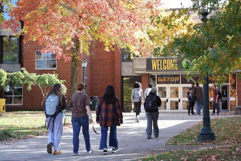 Allegheny College students walk toward the campus center, with a sign that reads 
