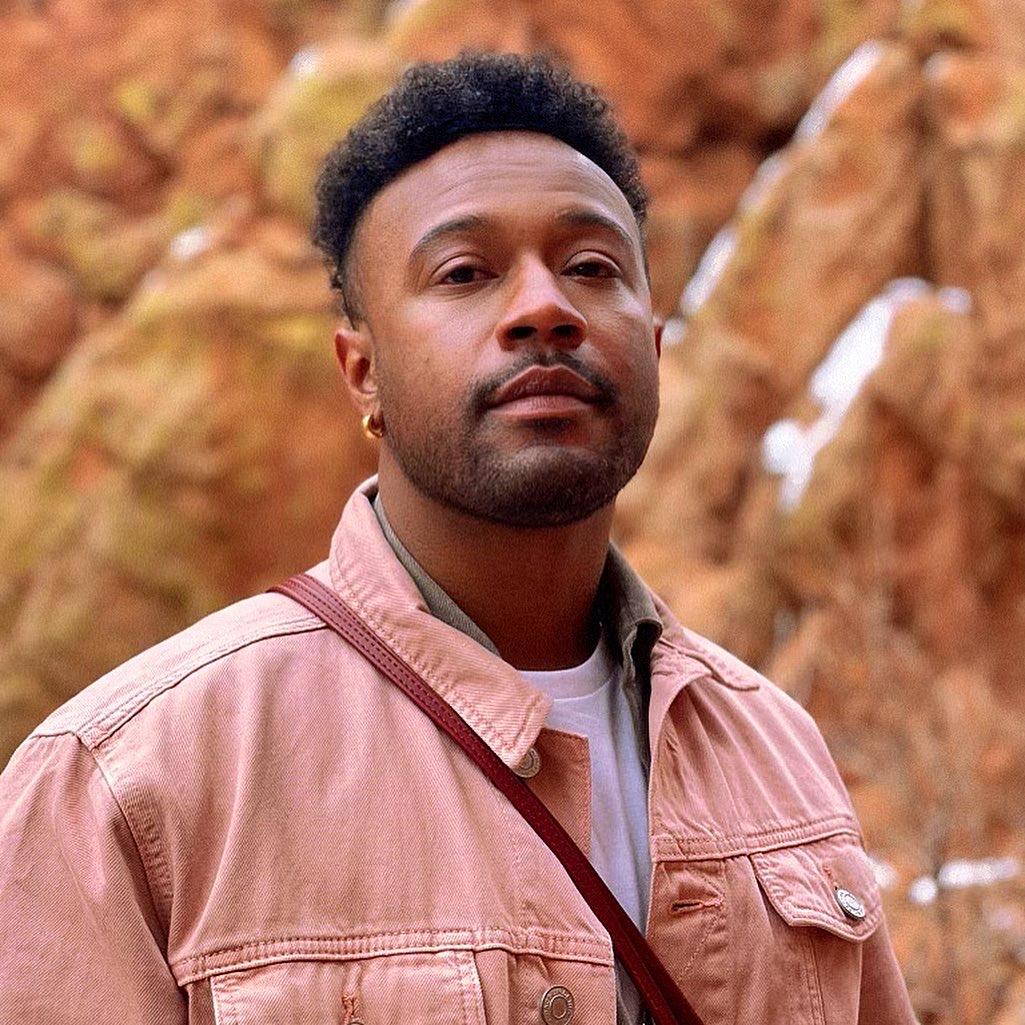 a person in a pink jacket in front of boulders