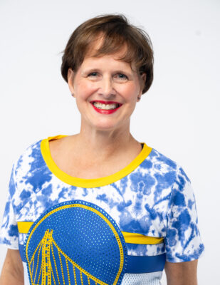 a woman in a blue and yellow shirt smiling at the camera