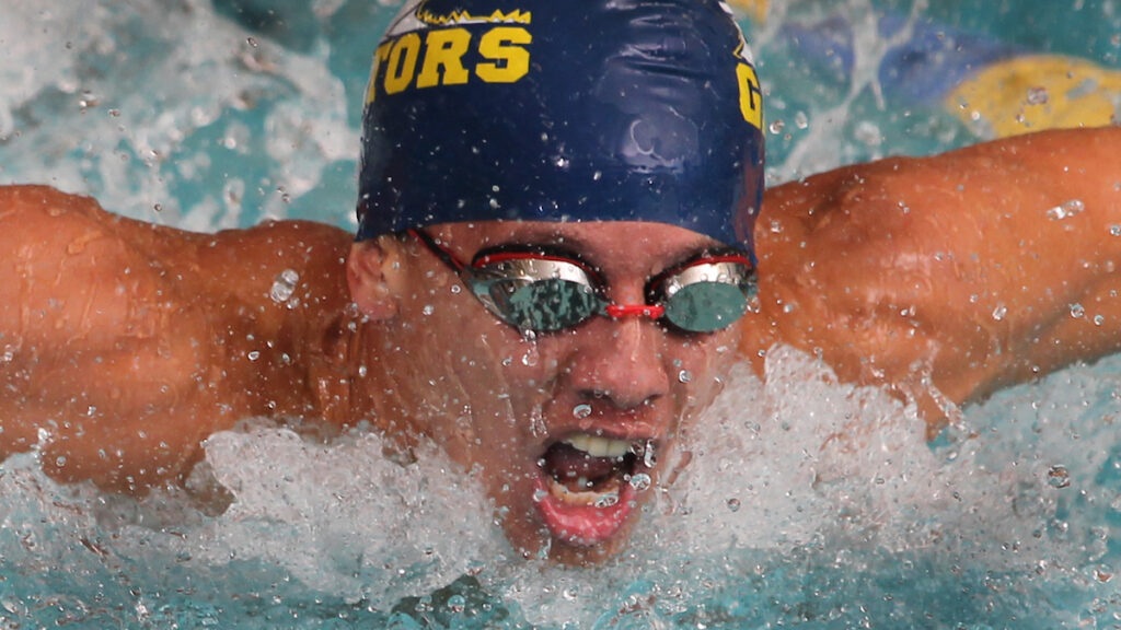 a closeup of a student wearing goggles swimming in a pool