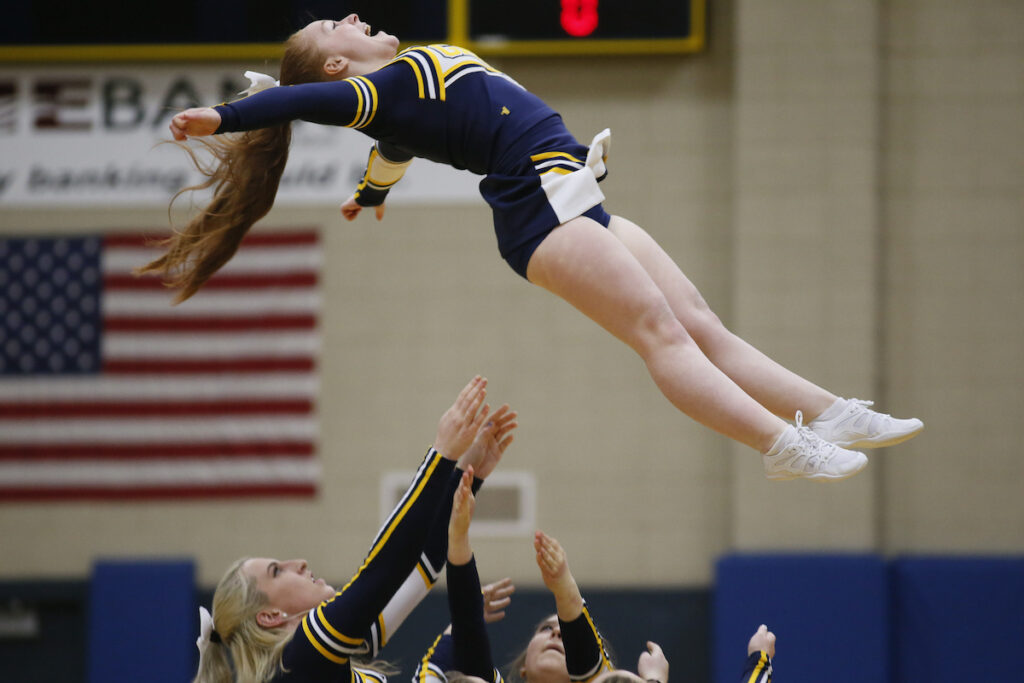 a cheerleader jumping in the air at a sports game