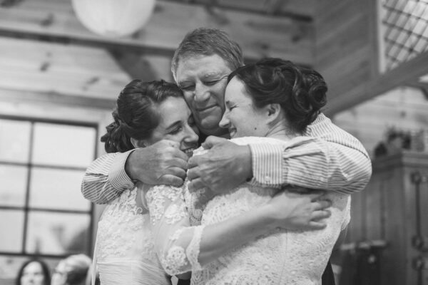 Bob Swartz '66 hugs Ellen Chamberlin '11 and her wife, Rebecca Beichner '11 at their wedding in Meadville in 2016