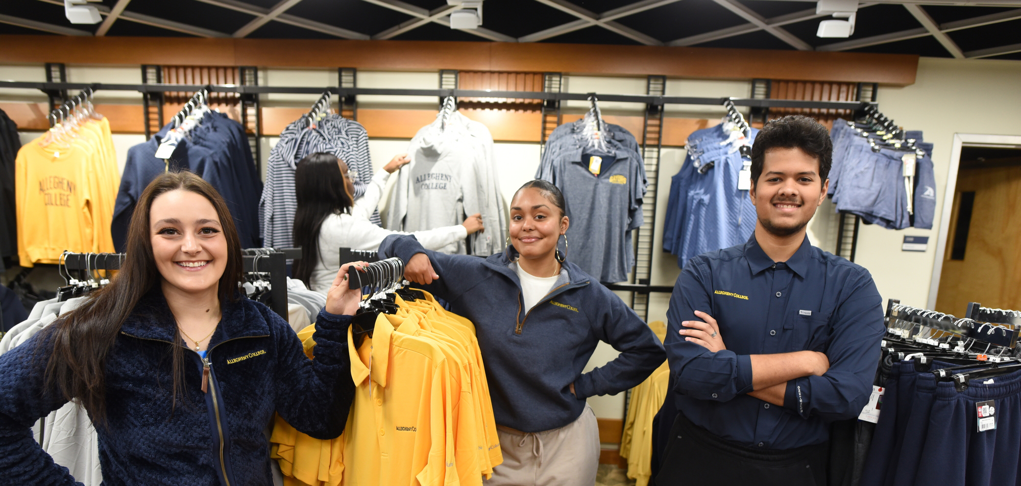 three students standing among the merchandise in the college campus store