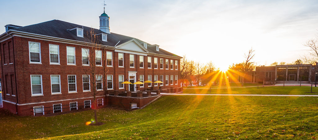 a large brick building with a green lawn
