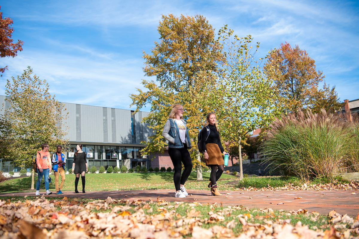 a group of two students walking on a path in the fall