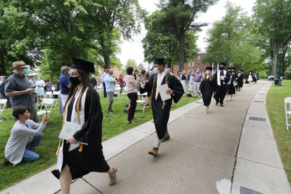a group of people in graduation gowns and hats walking down a sidewalk